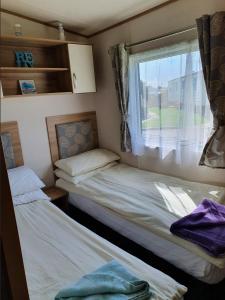 two beds in a small room with a window at Holiday Escapes in Selsey