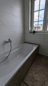 een badkamer met een wit bad en een raam bij Inheidener Neubau Ferienwohnung in Hungen