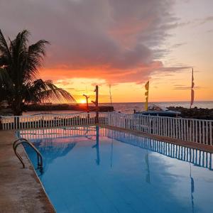 een zwembad naast het strand bij zonsondergang bij Medano Sunset Resort in Mambajao