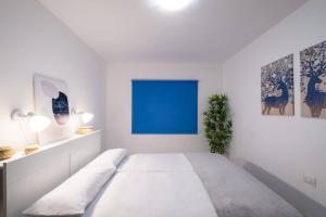 a white bedroom with a large bed and a blue window at Phoebe Apartment - city centre of Santa Cruz in Santa Cruz de la Palma