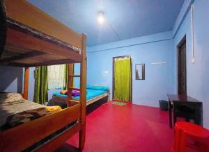 sypialnia z 2 łóżkami piętrowymi i czerwoną podłogą w obiekcie GREEN HILLS w mieście Czerapuńdżi