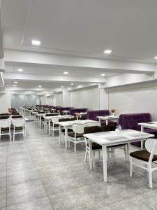 un comedor con mesas blancas y sillas moradas en Aurora Hotel, en Tashkent