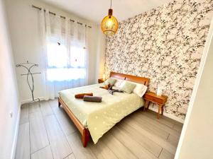 een slaapkamer met een bed en een muur met bloemen bij TODIMER Apartamento lujo in Motril