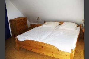 a bedroom with a wooden bed and a dresser at Deetje in Borkum