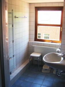 a bathroom with a sink and a chair and a window at Deetje in Borkum