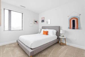 a white bedroom with a bed and a window at Spacious 2BR in Meridian Kessler by CozySuites in Indianapolis