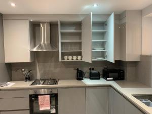 a kitchen with white cabinets and a stove at Icare Lodge Ltd,Safwaan House. in Barking