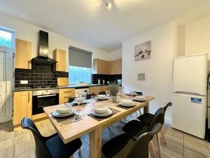 a kitchen with a wooden table with chairs and a refrigerator at Large 4 Bedroom Home, Close To Leeds City Centre in Kirkstall