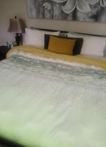 uma grande cama branca com uma almofada amarela em UHURU Gardens em eMatikwe