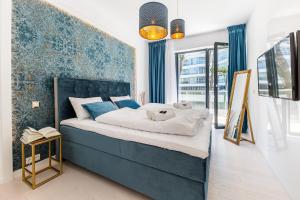 a bedroom with a large bed with a blue headboard at Dune Beach Resort in Mielno