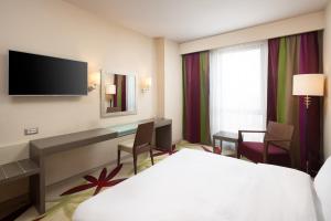 a hotel room with a bed and a desk at Golden Tulip Ana Dome Hotel in Cluj-Napoca