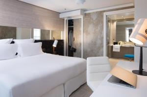 a bedroom with a large white bed and a bathroom at Hotel Dupond-Smith in Paris
