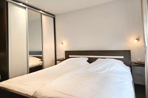 1 dormitorio con cama blanca y espejo en Vakantiebungalow Domburg DO01, en Domburg