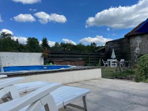 un patio con sillas blancas y una piscina en Maison Brandon, en La Chapelle-Montbrandeix