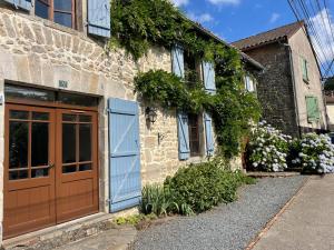 un edificio de piedra con una puerta azul y flores en Maison Brandon, en La Chapelle-Montbrandeix