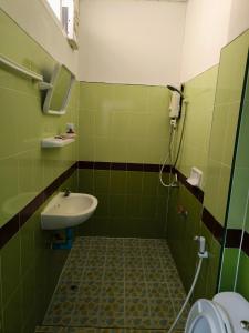 La salle de bains verte est pourvue d'un lavabo et de toilettes. dans l'établissement SB Betong ห้องพักรายวัน, à Betong