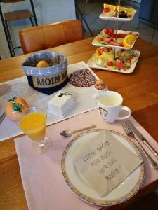 a table with a plate of food and a cup of orange juice at Gästehaus Nord-West 1700 - Einzelzimmer "Düne" in Steenfeld