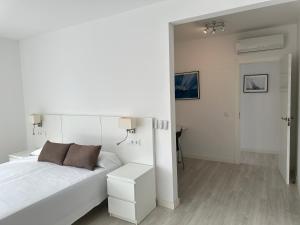 een witte slaapkamer met een bed en een tafel bij Agi Cap Llarg in Roses