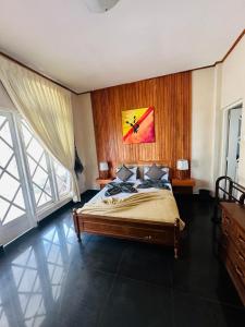1 dormitorio con 1 cama con una pintura en la pared en Maples Holiday Resort, en Nuwara Eliya