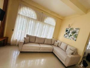 sala de estar con sofá y ventana grande en Maples Holiday Resort, en Nuwara Eliya