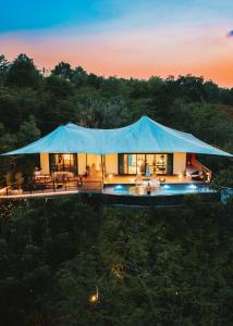 Te Mata Glamping في Nong Nam Daeng: منزل في وسط غابة مع خيمة زرقاء