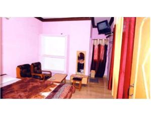 a bedroom with a bed and a chair and a tv at Hotel Narmada Bhawan, Badrinath in Badrīnāth