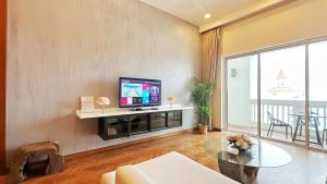 een woonkamer met een tv en een glazen tafel bij Straits Quay Marina Suites in Tanjong Tokong