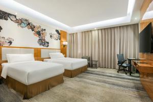 a hotel room with two beds and a flat screen tv at MIZPARTON HOTEL - Heshan New Town in Jiangmen