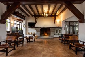 a living room with a fireplace and tables and chairs at Hotel Tugasa Las Truchas in El Bosque