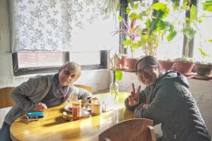 Dos mujeres sentadas en una mesa con signos de paz en Traditional Newari Homestay, en Pātan