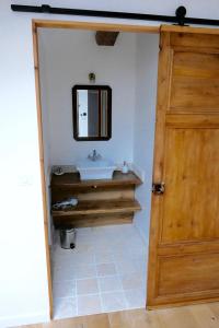 a bathroom with a sink and a wooden door at La Garoffe in Pibrac