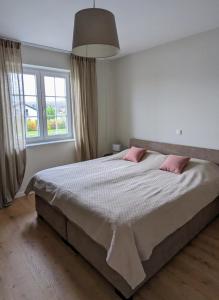 een slaapkamer met een groot bed met 2 roze kussens bij Inheidener Neubau Ferienwohnung in Hungen