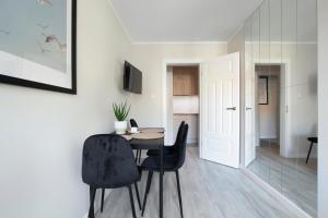 a dining room with a table and black chairs at Elite Apartments Garncarska Classy in Gdańsk