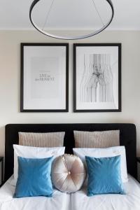 a bedroom with two framed pictures and a bed with blue pillows at Elite Apartments Garncarska Classy in Gdańsk