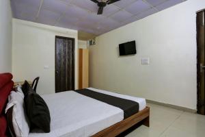 a bedroom with a bed and a tv on the wall at Omi Inn Manesar in Manesar
