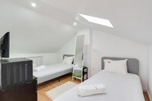 Duas camas num quarto com televisão e espelhos em Hopstays - Almada Getaway em Almada