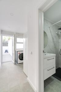 uma cozinha branca com um lavatório e uma máquina de lavar roupa em Hopstays - Almada Getaway em Almada