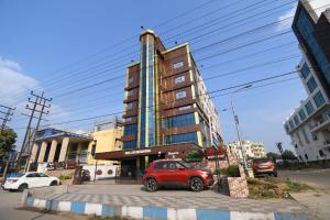 Āsansol的住宿－Hotel Jyoti International，停在高楼前的红色汽车