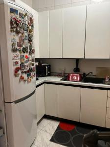 a kitchen with white cabinets and a refrigerator with magnets at casa vacanza trastevere in Rome