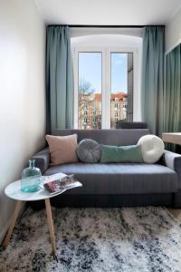 a living room with a blue couch and a window at Elite Apartments Garncarska Classy in Gdańsk