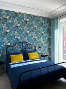 1 dormitorio con cama azul y papel pintado con motivos florales en B&B Vittoria, en Anzio
