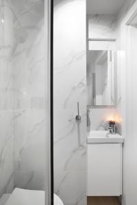 a white bathroom with a sink and a mirror at Elite Apartments Garncarska Classy in Gdańsk