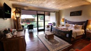 a bedroom with a large bed and a living room at Kupu Kupu Barong Villas and Tree Spa by L’OCCITANE in Ubud