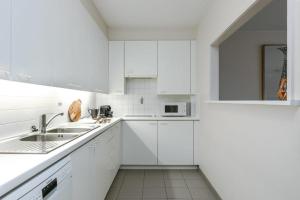 een witte keuken met witte kasten en een wastafel bij Apartment Alios in Oostende