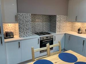 cocina con armarios blancos, mesa y fogones en Wood Green Budget Rooms - Next to Mall & Metro Station - 10 Min to City Center en Londres