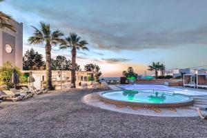 una piscina con palmeras y un edificio en Gouves Bay by Omilos Hotels, en Gouves
