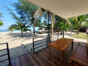 Loma Beach Resort في Ban Pak Nam Pak Duat: شرفة مع طاولة خشبية وإطلالة على الشاطئ