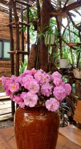 un jarrón lleno de flores rosas sentado en una mesa en 1996 Homestay Măng Đen, en Kon Von Kla