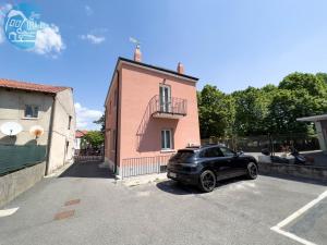 un coche negro estacionado frente a un edificio rosa en Basovizza 3 Chanel Tirabora Short Rent, en Villa Opicina