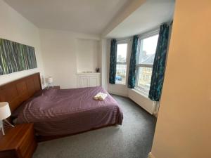 1 Schlafzimmer mit einem lila Bett und 2 Fenstern in der Unterkunft Kingfisher En-suite Room in Plymouth